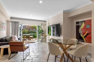 a living room with a glass table and chairs at Rose Gold Hideaway in Kings Park