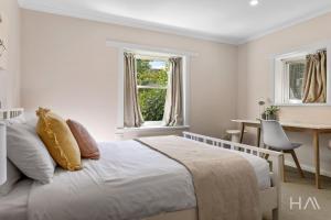 a bedroom with a bed and a desk and windows at Rose Gold Hideaway in Kings Park