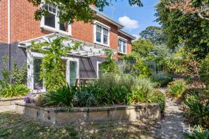 a garden in front of a brick house at Rose Gold Hideaway in Kings Park
