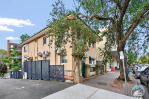 a building with a tree next to a street at Stylish 4-Bed Loft in Manly Walk to Beach & Ferry in Sydney