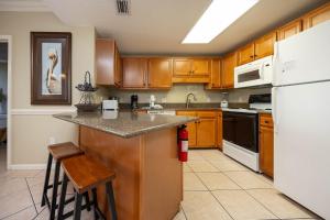 a kitchen with wooden cabinets and a white refrigerator at Phoenix X 211 condo in Orange Beach
