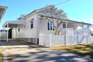 ein weißes Haus mit einem weißen Zaun davor in der Unterkunft Christina Cottage - Bring your own linen in South West Rocks