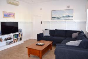 ein Wohnzimmer mit einer blauen Couch und einem Couchtisch in der Unterkunft Christina Cottage - Bring your own linen in South West Rocks