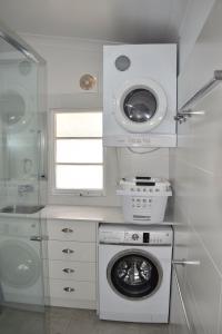 eine Waschküche mit einer Waschmaschine und einem Fenster in der Unterkunft Christina Cottage - Bring your own linen in South West Rocks