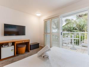 une chambre avec un lit et une télévision et un balcon dans l'établissement The Pool Resort Kingscliff - 2BR Dual Key and 1BR (7303/7304) - Holiday Management Co., à Kingscliff