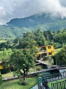a yellow house on the side of a river at Chick Resort Khao Kho in Khao Kho