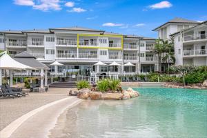 un complexe avec une piscine et un bâtiment dans l'établissement The Pool Resort Kingscliff - 2BR Dual Key and 1BR (7303/7304) - Holiday Management Co., à Kingscliff