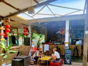 two women are sitting at a table in a building at The Bear Bungalow in Kampot