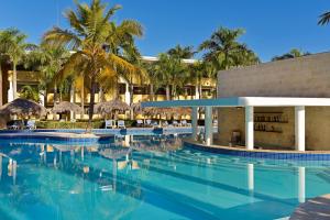 a resort swimming pool with palm trees in the background at Iberostar Costa Dorada in San Felipe de Puerto Plata