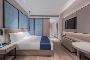 una camera da letto con un letto grande e una televisione di Echarm Hotel Nanning East Railway Station a Tunli