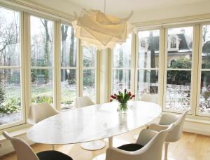 a dining room with a white table and chairs and windows at Het Bosch in Bergen