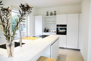 a kitchen with white cabinets and a vase with a plant at Het Bosch in Bergen