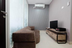 a living room with a couch and a television at Clean and Cozy 1BR Apartment with Sofabed at Atlanta Residences By Travelio in Depok