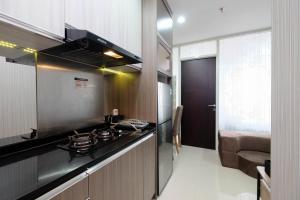 a kitchen with a stove top oven in a room at Clean and Cozy 1BR Apartment with Sofabed at Atlanta Residences By Travelio in Depok