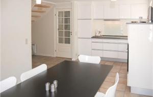 a kitchen with a black table and white cabinets at Three-Bedroom Holiday Home In Blavand in Blåvand
