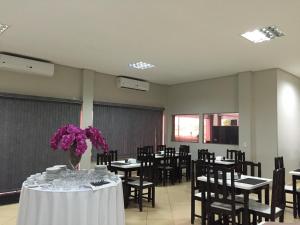 a dining room with tables and chairs and purple flowers at Hotel Notre Dame in Luís Eduardo Magalhães