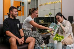 three people sitting in an office with a woman pointing at a laptop at Dream Premium Hotel & Spa in Hanoi