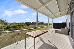 a deck with a table and a couch on a house at Newly built with WiFi & Healthclub, pool & gym access in Inverloch