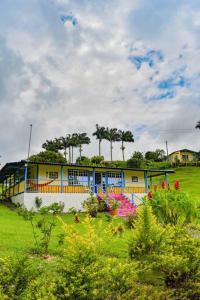 a yellow and blue house in a field with flowers at Alojamiento campestre villa Gabriela filandia in Filandia