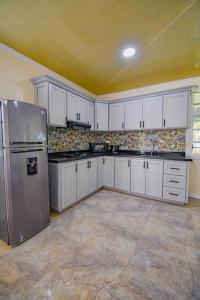 a kitchen with white cabinets and a stainless steel refrigerator at Alojamiento campestre villa Gabriela filandia in Filandia
