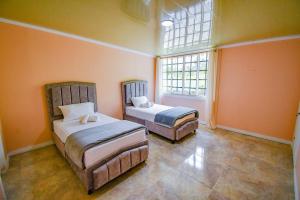 two beds in a room with orange walls and a window at Alojamiento campestre villa Gabriela filandia in Filandia