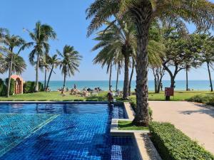 a swimming pool with palm trees and the beach at Marrakesh Residence HuaHin BunkBed Family Room in Hua Hin