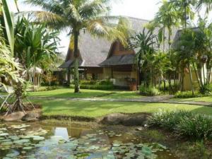 a house with a pond in front of it with palm trees at Tanjung Lesung Beach Hotel in Kalicaah