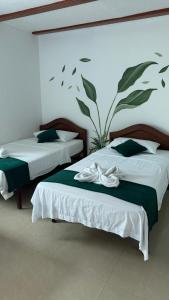 two beds with green and white sheets in a room at Hotel Rodadero Relax in Gaira