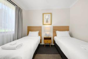 two twin beds in a room with a window at Melview Greens - Two-Bedroom Apartment in Orange +25 photos