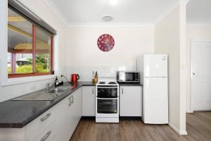 a kitchen with white appliances and a white refrigerator at Melview Greens - Two-Bedroom Apartment in Orange