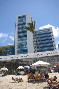 un grupo de personas sentadas en una playa con sombrillas en Apartamento Salvador VIP, en Salvador