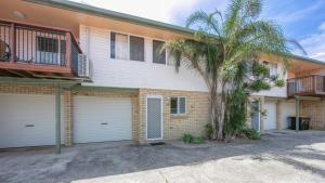 a house with two garage doors and a palm tree at The Palms 3 in Iluka