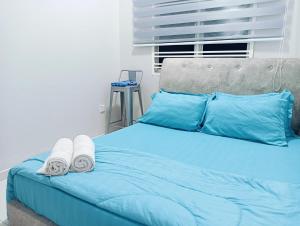 a blue bed with blue pillows and towels on it at Santai Homestay PD in Port Dickson +11 photos