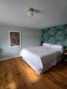a bedroom with a white bed and a painting on the wall at Seaview in Stornoway