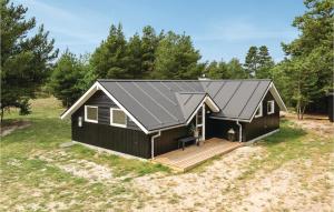 a black house with a porch and a deck at Four-Bedroom Holiday Home In Blavand in Blåvand