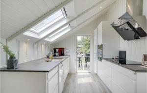 a kitchen with white cabinets and a skylight at Four-Bedroom Holiday Home In Blavand in Blåvand