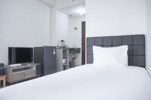 une chambre avec un grand lit et une télévision dans l'établissement Cozy Living Studio Transpark Cibubur near Shopping Center Apartment By Travelio, à Depok