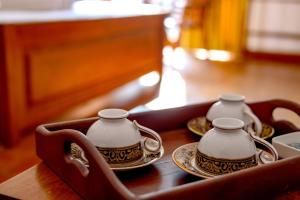 a tray with three tea cups and plates on a table at Urban Garden Vacation Rental in Kandy