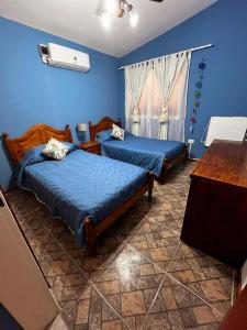 two beds in a room with blue walls at Acogedora casa Vacacional en Valle Hermoso Cordoba in Valle Hermoso