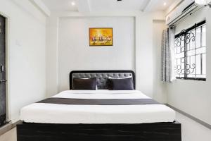 a bedroom with a large bed with a black headboard at Hotel O Grand Trinity in Nagpur