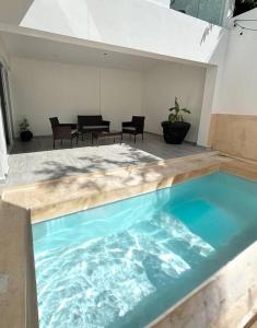 a swimming pool in a room with chairs and tables at A nice like a local Villa house - Casa Encuentro Tulum in Tulum