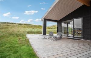 a wooden deck with two chairs and a table on it at Holiday Home Hvide Sande 25 in Bjerregård +19 photos