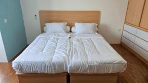 a bed with white sheets and pillows in a room at Apartemen Permata Residences Homestay Baloi in Nagoya