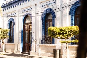 a white building with blue arches and doors at Casa de hospedaje -La Abadía de San Pedro in Guadalajara