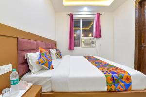 a bedroom with a large white bed with colorful pillows at FabHotel Hari Residency in Haridwār +27 photos
