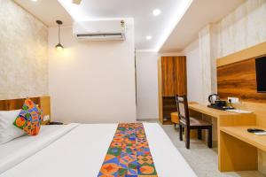 a hotel room with a bed and a desk at FabHotel Sonali Golden Palace - Nr Bhubaneswar Railway Station in Bhubaneshwar