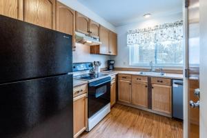 una cucina con armadi in legno e frigorifero nero di 4BR Private Townhouse at Smugglers' Notch Resort condo a Jeffersonville