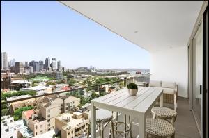 a balcony with a white table and chairs and a city at Stylish Double Storey Apt plus Harbour Bridge Views! in Sydney