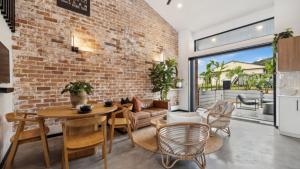 a brick wall in a living room with a table and chairs at Catalyst Retreat - Stylish, Pets, Accessible, Sauna in Coffs Harbour