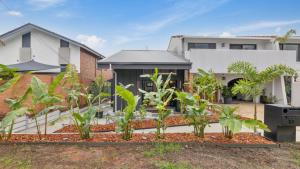 a garden in front of a house with plants at Catalyst Retreat - Stylish, Pets, Accessible, Sauna in Coffs Harbour
